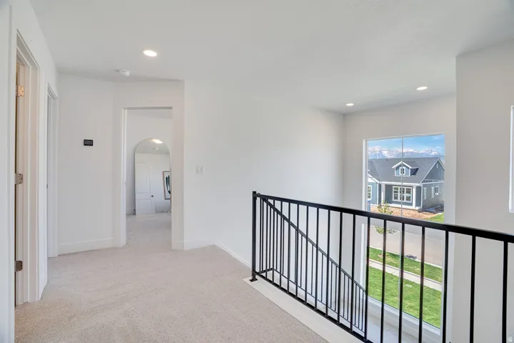 Upper-level hallway with neutral carpeting, recessed lighting, and white walls
