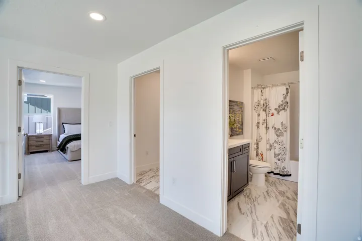 Plush carpeting, recessed lighting, and a bathroom featuring a dark wood-finish vanity with a white countertop and tile flooring