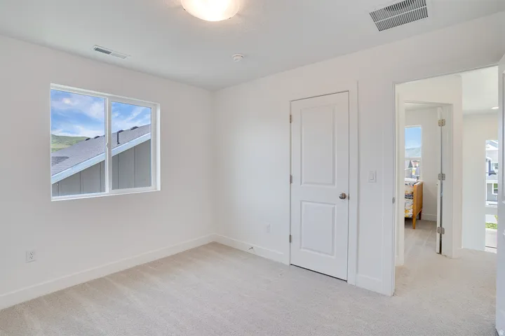 Neutral wall finishes, recessed lighting, white trim details, and light-toned carpeting