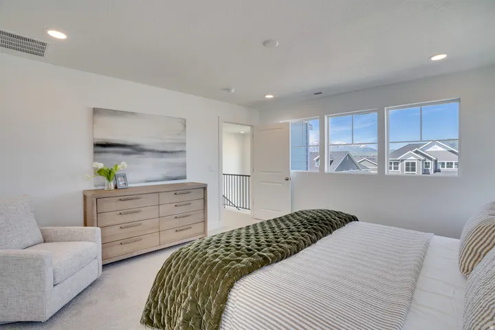 White painted walls, recessed lighting, carpet flooring, three large windows, and a white door with a metal handle