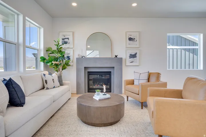 Recessed lighting, light wood-finish flooring, and a built-in fireplace featuring a concrete surround