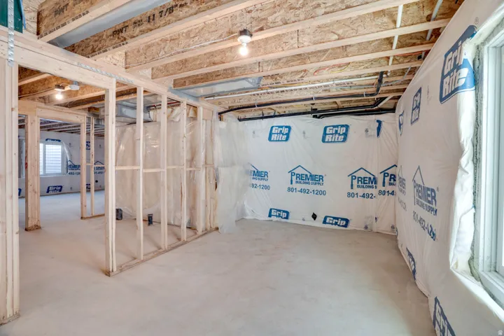 Unfinished basement with wood framing, exposed ceiling joists, concrete flooring, and a single window