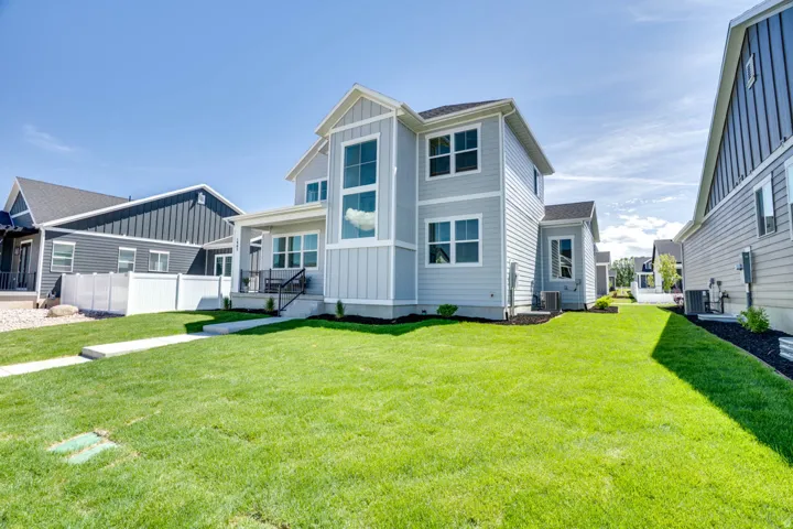Light gray siding exterior with vertical accent panels, covered porch entry, multiple large windows, and a paved walkway