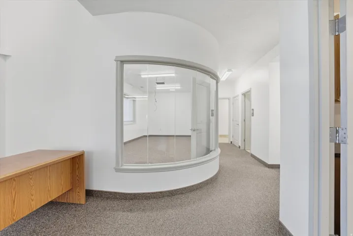 Curved glass wall office space with neutral carpet flooring and white walls