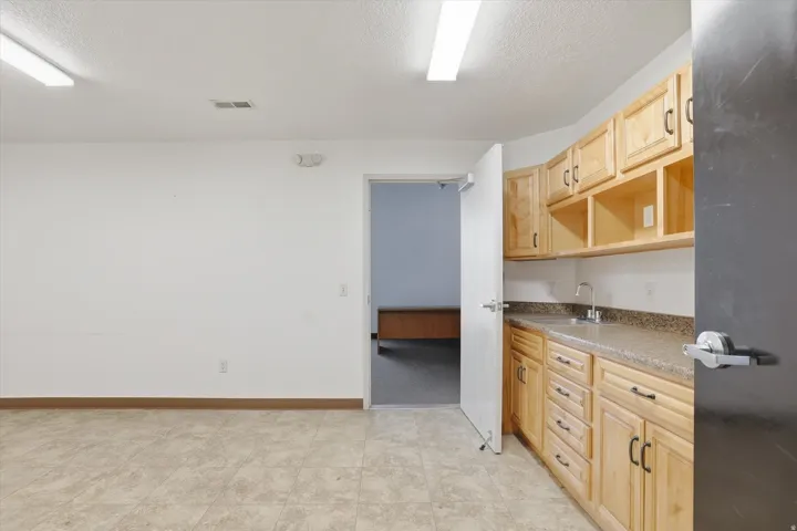 Tile flooring and light wood-finish cabinetry with dark hardware