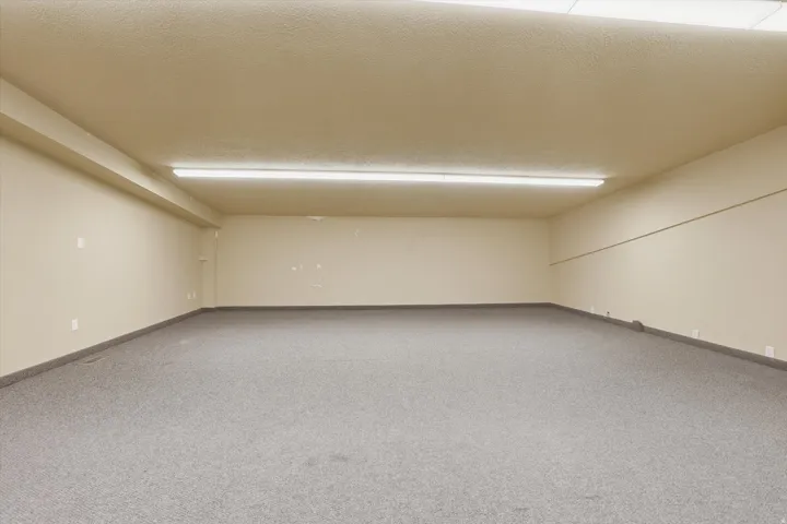 Spacious room featuring neutral-toned walls, textured ceiling, and grey carpet flooring