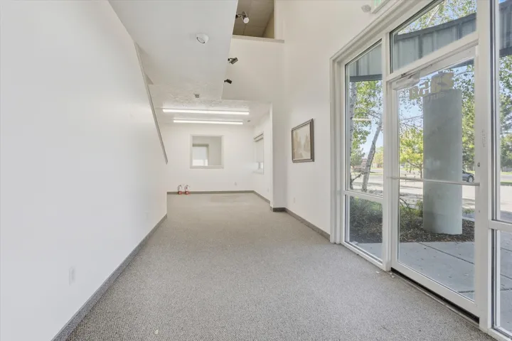 Full-light glass entry door, full-height windows, neutral wall finishes, and light-colored carpet flooring