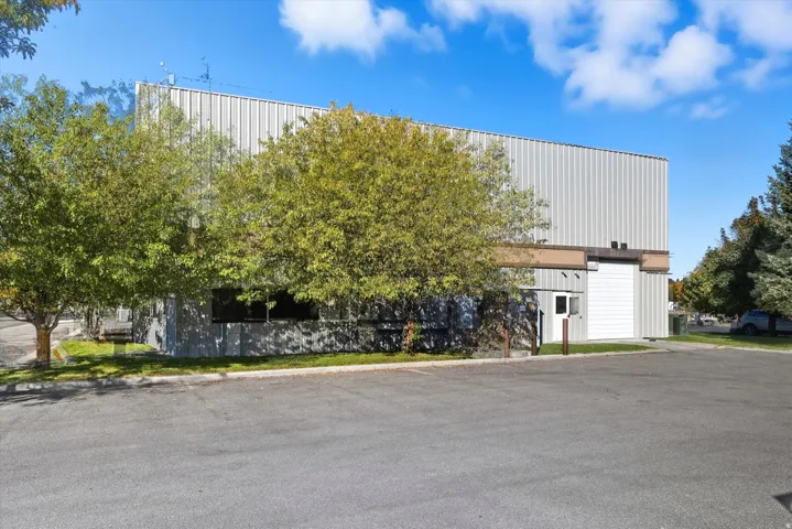 Industrial building featuring corrugated metal siding, an overhead door, and a dedicated entry door