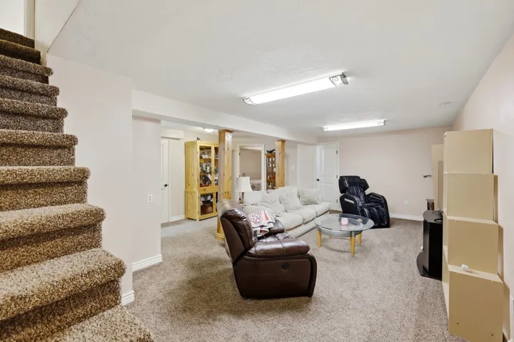 Carpeted staircase opening to a spacious room with recessed lighting and carpet flooring