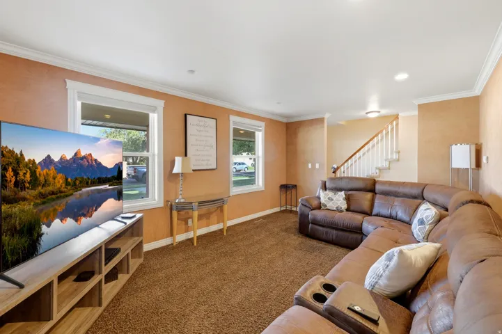 Spacious living area featuring neutral-toned walls, contrasting white trim, and a carpeted floor