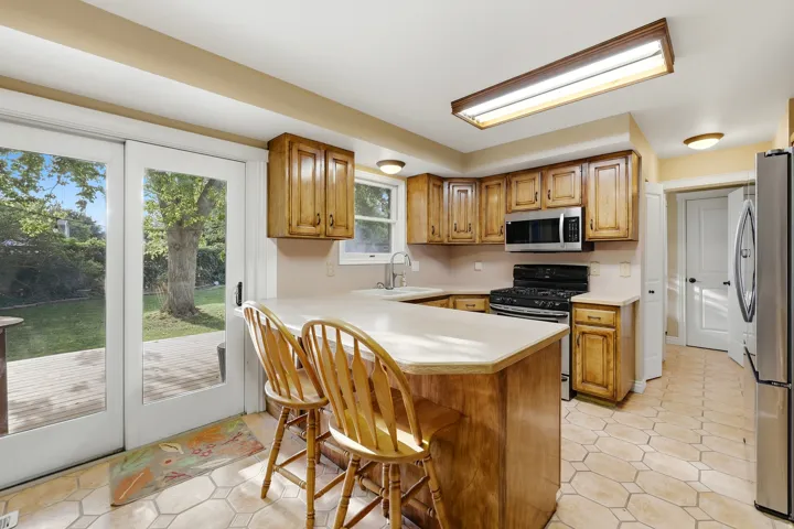 Kitchen featuring wood cabinetry, stainless steel appliances, a kitchen island with seating, and sliding glass doors leading to an outdoor patio
