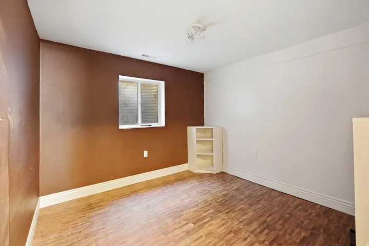 Wood-finish flooring with white trim and a built-in corner shelving unit