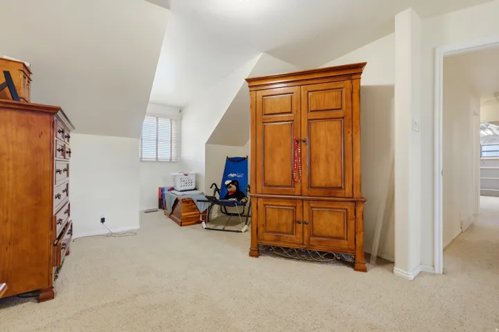 Carpeted room featuring a sloped ceiling, recessed window, and white painted walls