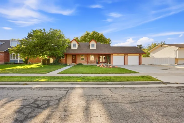 Dormer windows, dual garage doors, front porch, and mature landscaping