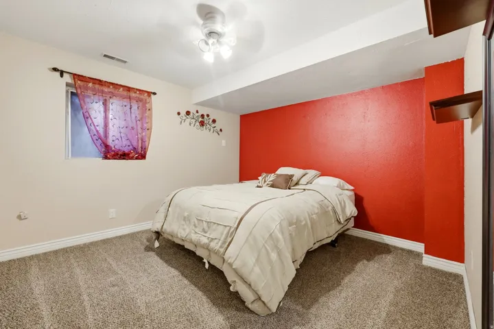 Carpeted room featuring a single window, a ceiling fan, and a built-in wall shelf