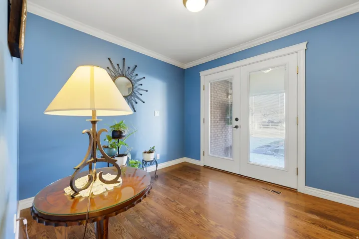 French doors with clear glass panes, wood-finish flooring, crown molding, and white door trim