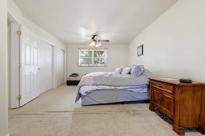 Recessed window with blinds, ceiling-mounted fan with light fixture, and carpeted flooring