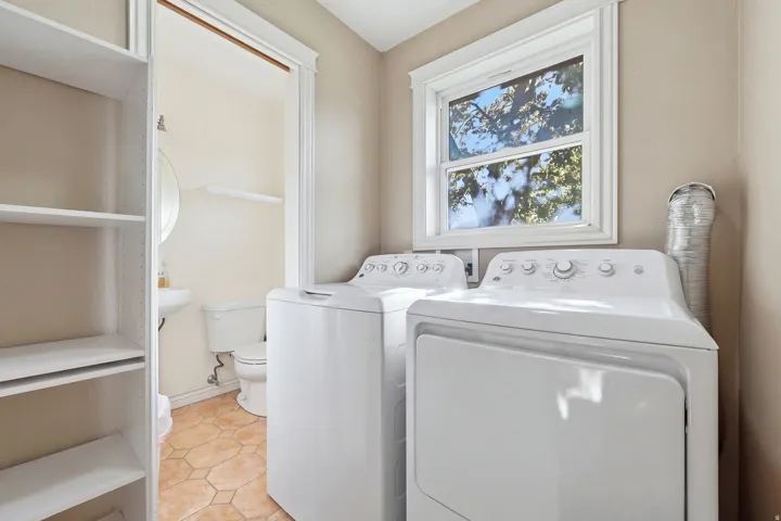Dedicated laundry area featuring a window, built-in shelving, and tile flooring