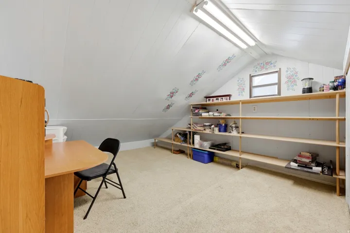 Sloped ceilings with exposed beams, window, built-in shelving, carpet flooring, and integrated lighting