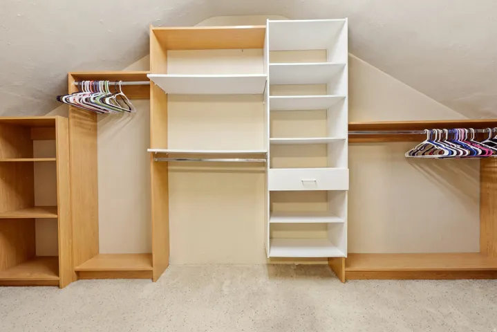 Custom closet system featuring open shelving, hanging rods, and a central drawer