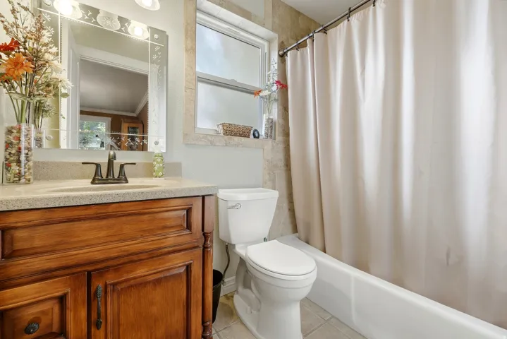 Vanity with wood-finish cabinetry, countertop with integrated sink, and an ornate mirror