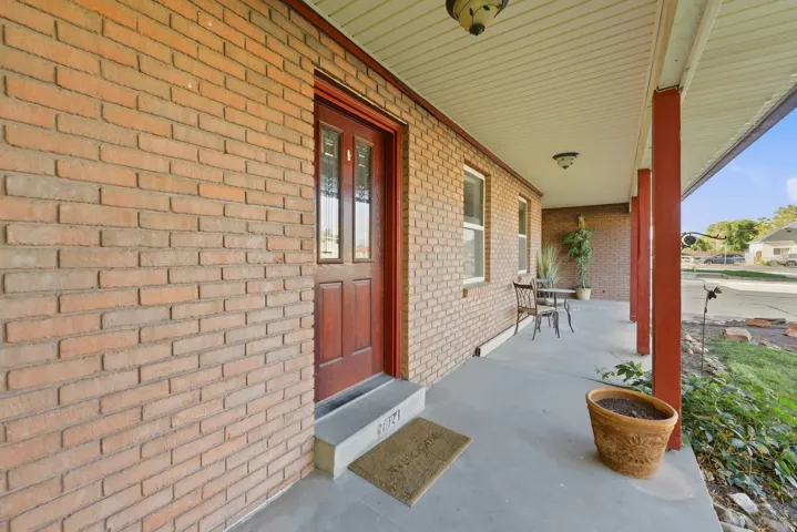 Brick exterior with a covered porch, wood-paneled entry door with glass inserts, and multiple windows