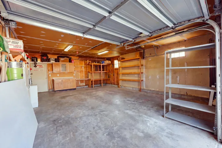 Concrete floor, built-in cabinetry, overhead fluorescent lighting, built-in shelving, and a small transom window