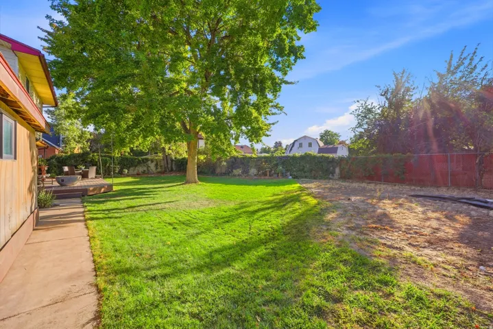 Expansive lawn area with mature tree, concrete walkway, and a raised wooden deck