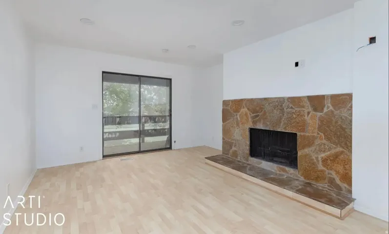 Stone-clad fireplace with hearth, wood-finish flooring, recessed lighting, and sliding glass doors