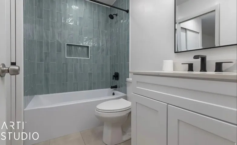 White vanity with a light-toned countertop, matte black faucet, and rectangular mirror