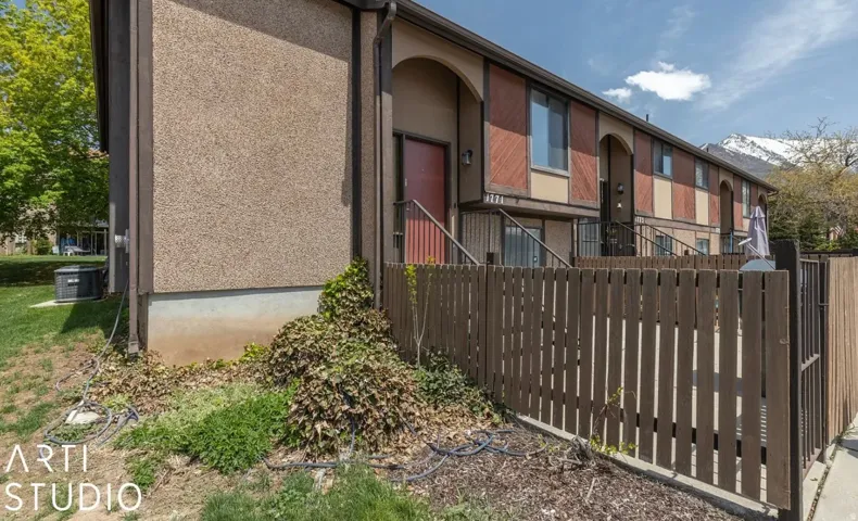 Exterior facade featuring stucco and wood paneling, private fenced patio, and a mountain backdrop