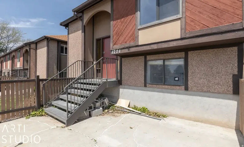 Exterior featuring a red entry door, an arched entryway, and a dark-toned staircase with metal railings