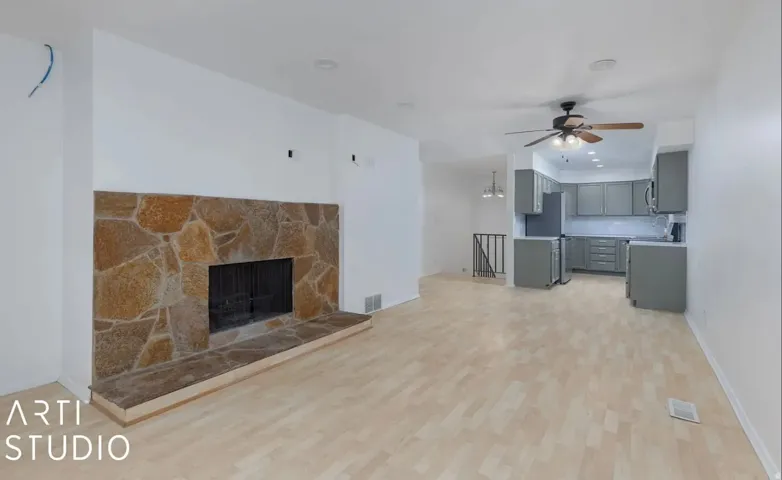 Living area featuring a stone-faced fireplace with a hearth, wood-finish flooring, and recessed lighting