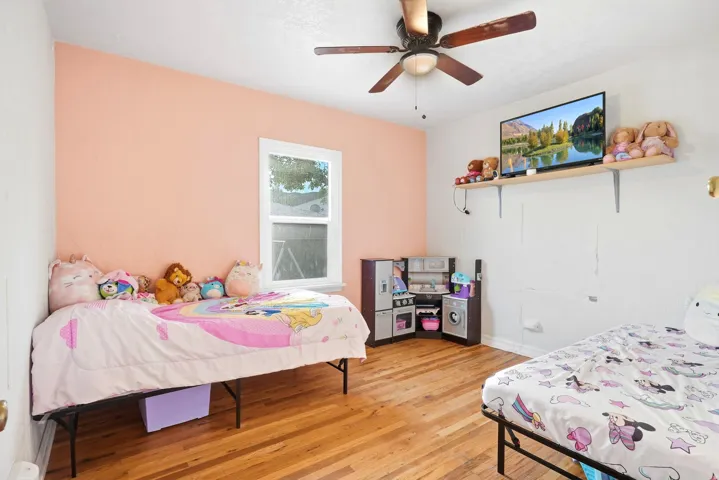 Hardwood-finish flooring, ceiling fan with integrated lighting, and a window with white trim