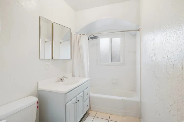 Bathroom featuring a single vanity with built-in storage, a tub-shower combination, and tiled flooring