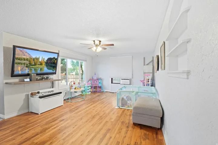 Wood-finish flooring throughout, ceiling fan, built-in shelving, and sliding glass doors