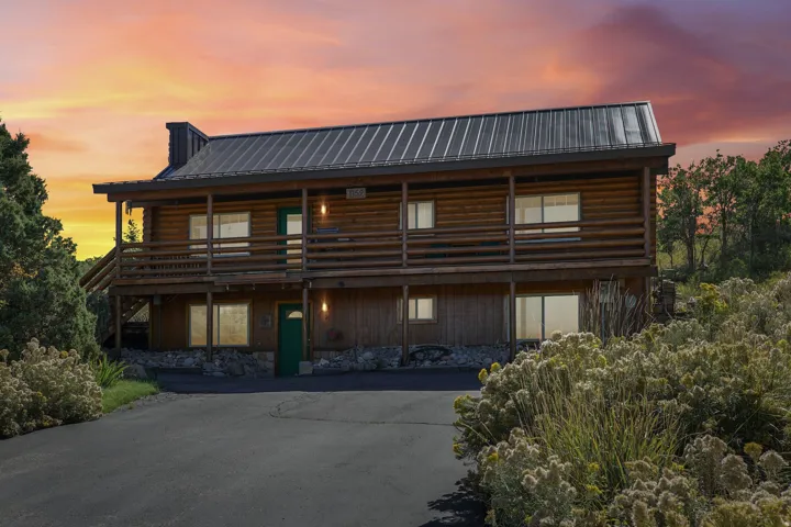Log-style exterior with a metal roof, stone foundation, and a full-width upper-level balcony