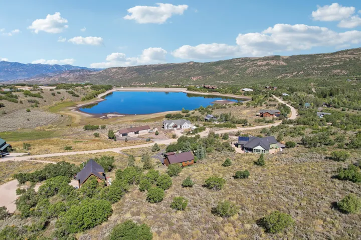Expansive property featuring a tranquil lake, surrounding natural landscape, and distant mountains
