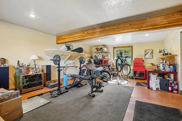 Spacious bonus room featuring exposed wood beams, recessed lighting, a window with wood trim, and versatile flooring options