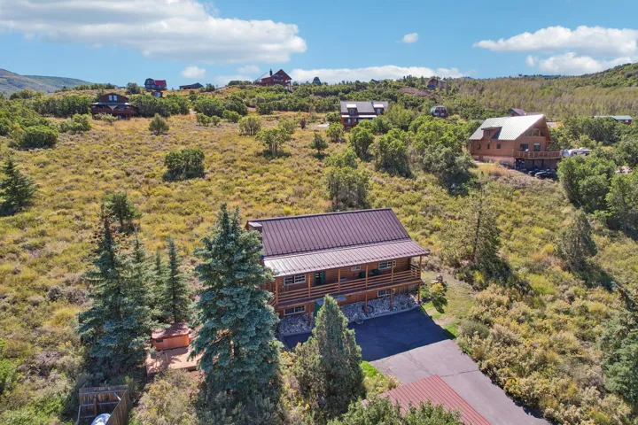 Wood-sided property with a metal roof, an elevated deck, and a stone foundation