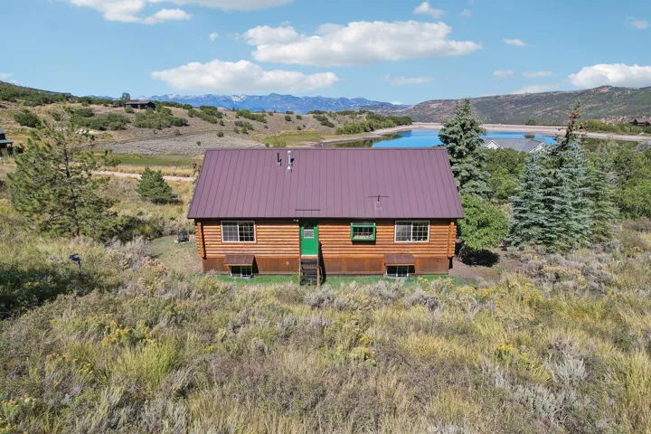 Log cabin exterior with a metal roof, green entry door, and multiple windows