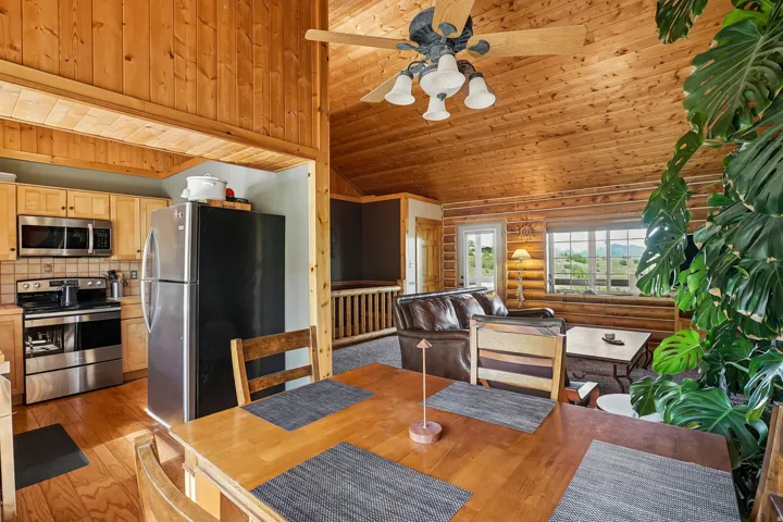 Vaulted wood-finish ceilings, wood-finish flooring, log wall construction, stainless steel kitchen appliances, and exposed wood beams