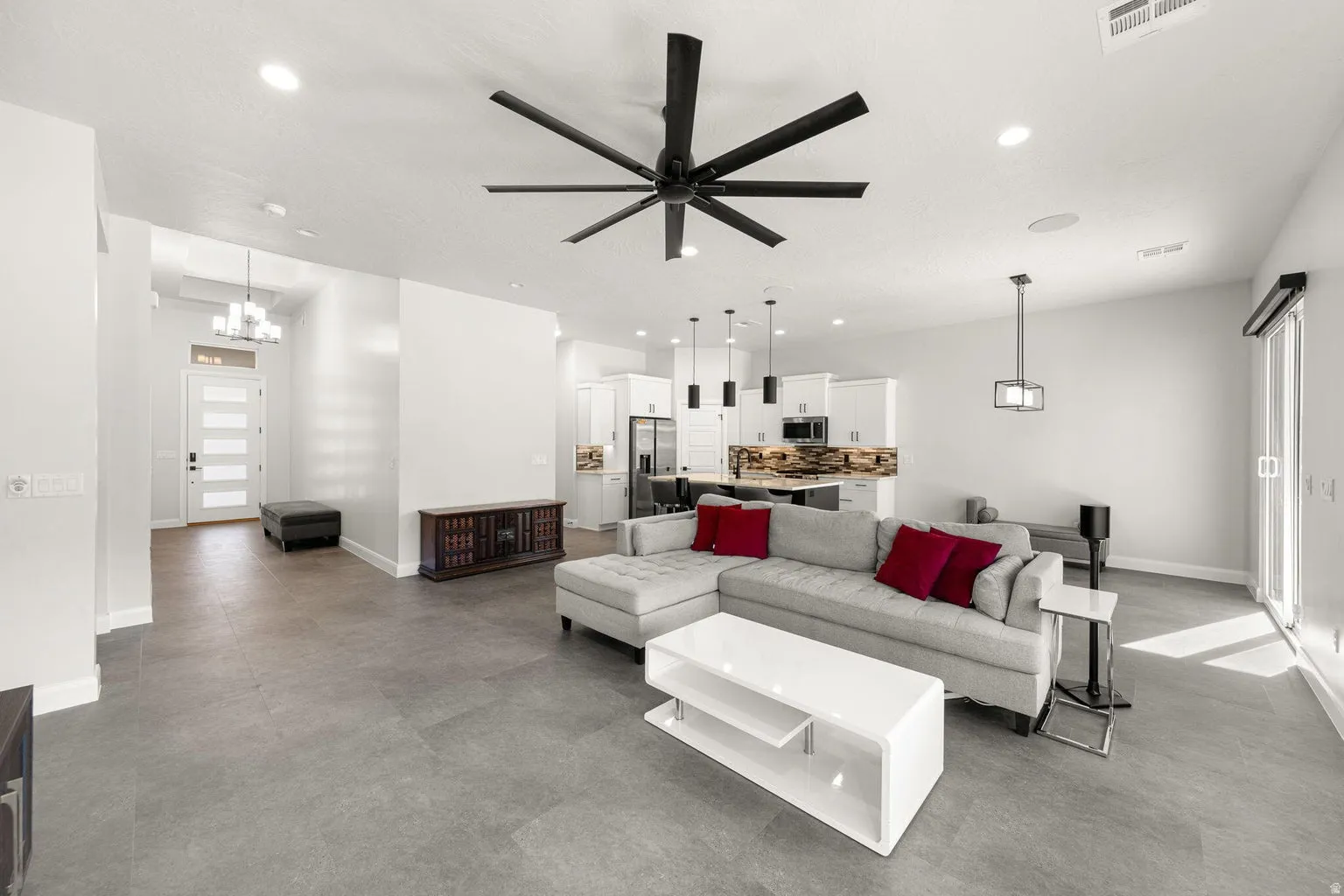 Spacious living area featuring a large ceiling fan, recessed lighting, and tile flooring