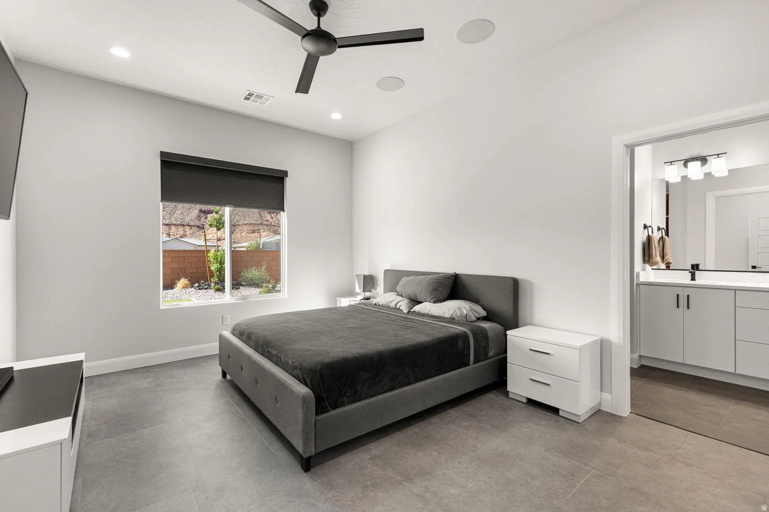 Recessed lighting, ceiling fan, hard surface flooring, window with roller shade, and an en-suite bathroom with vanity