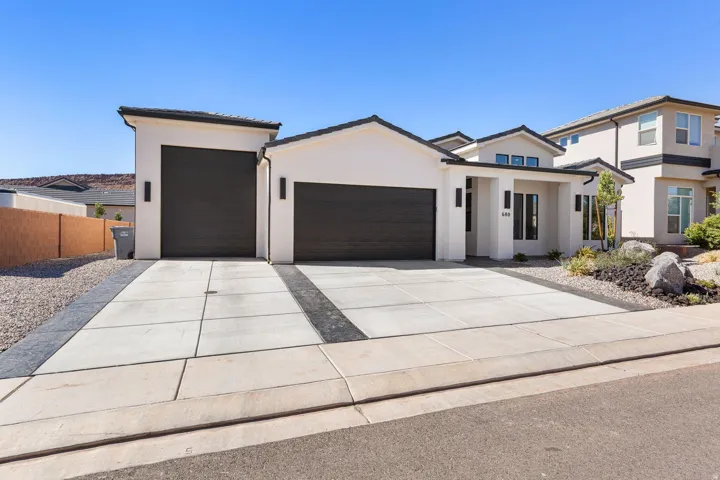 Contemporary stucco exterior with dark trim and a dual garage