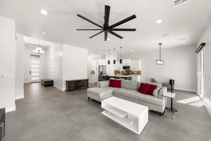 Spacious living area featuring a large ceiling fan, recessed lighting, and tile flooring