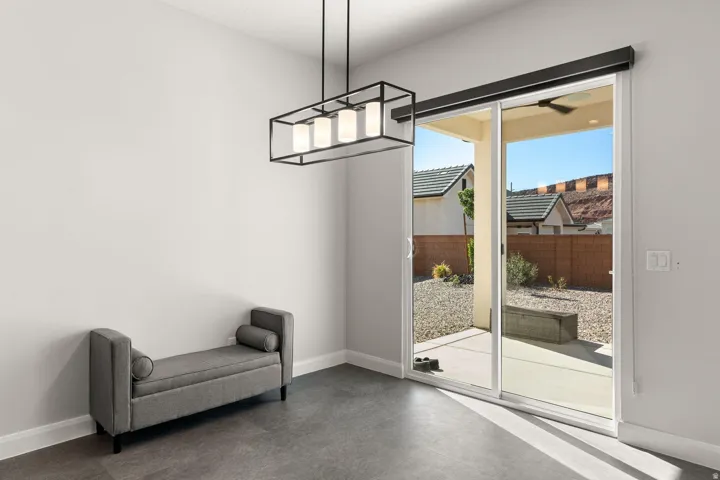 Sliding glass door to the exterior patio, overhead linear chandelier, and wood-finish flooring