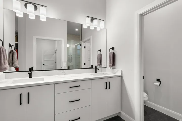 Dual vanity with integrated rectangular sinks, expansive countertop, white cabinetry, and matte black hardware