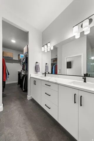 Double vanity with white cabinetry, matte black hardware, and an expansive mirror