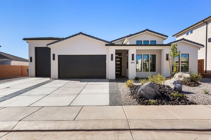 Contemporary exterior with a white stucco finish, dark tile roof, and integrated two-car garage